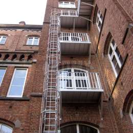Escalera de incendios de 3 pisos con jaula con balcones de acceso en cada piso para una fábrica.