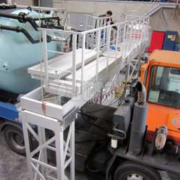 Plataforma pivotante industrial de aluminio utilizada para acceder a equipos de remolques cisterna para mantenimiento.